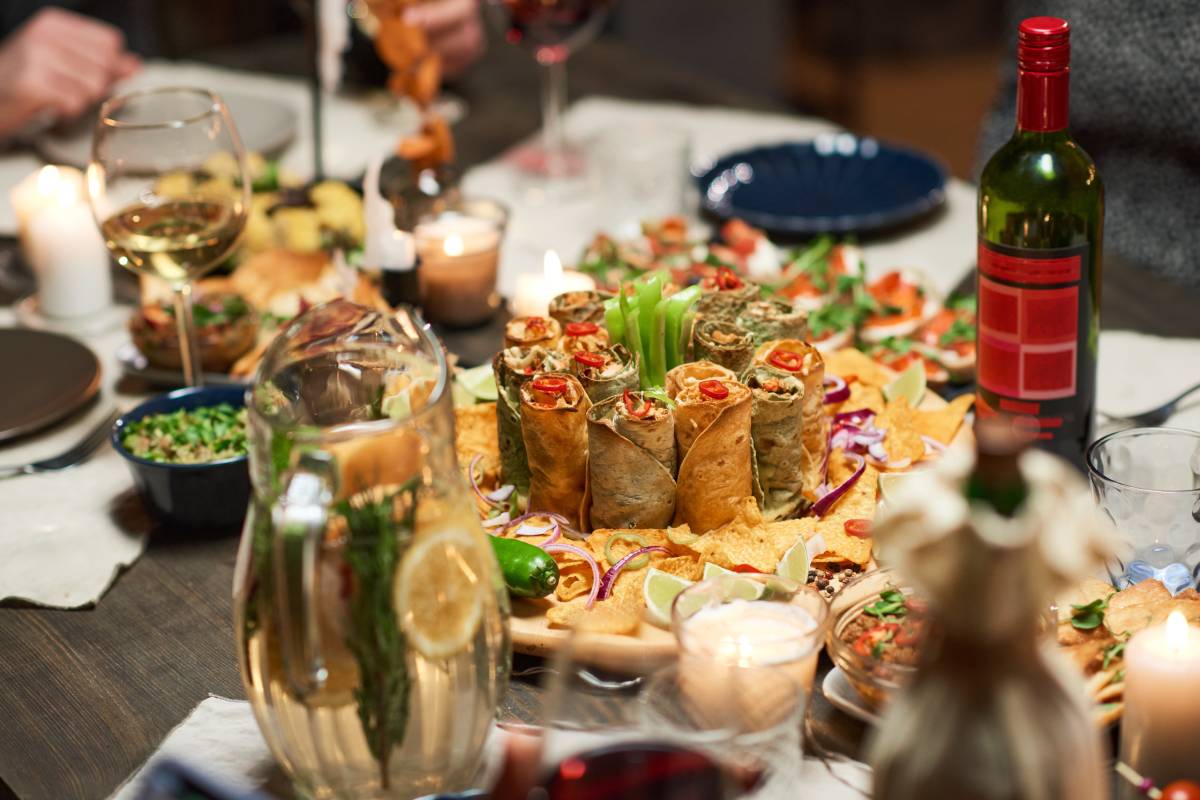 Close-up of different delicious appetizers and bottle of red wine on wedding catering dining table