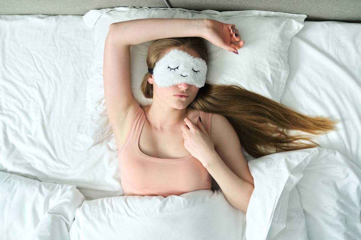 Young woman with long blonde hair with sleep mask in her eyes sleeping