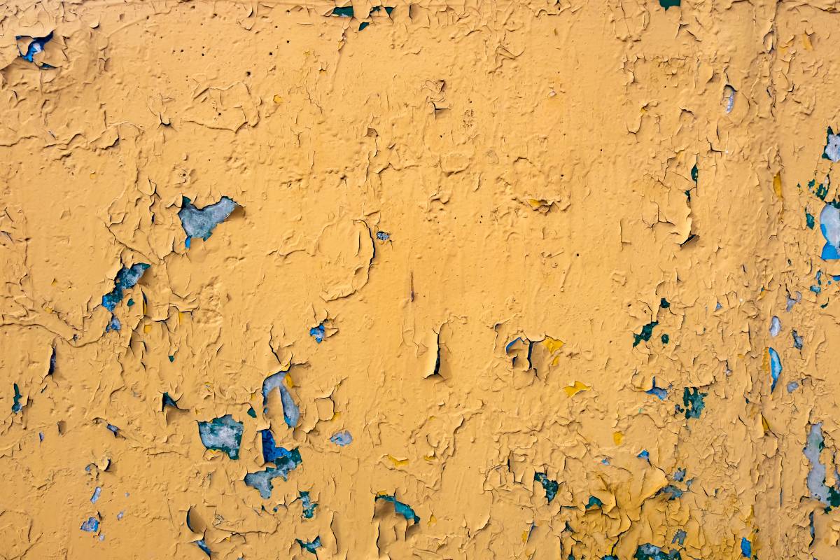 cracked yellow paint on blue concrete wall