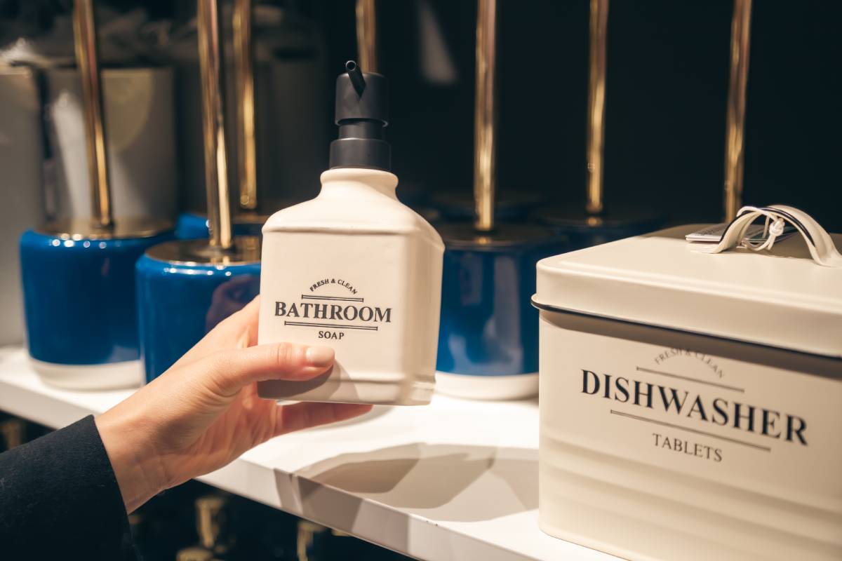 Woman choosing soap bottle for bathroom at the interior market.
