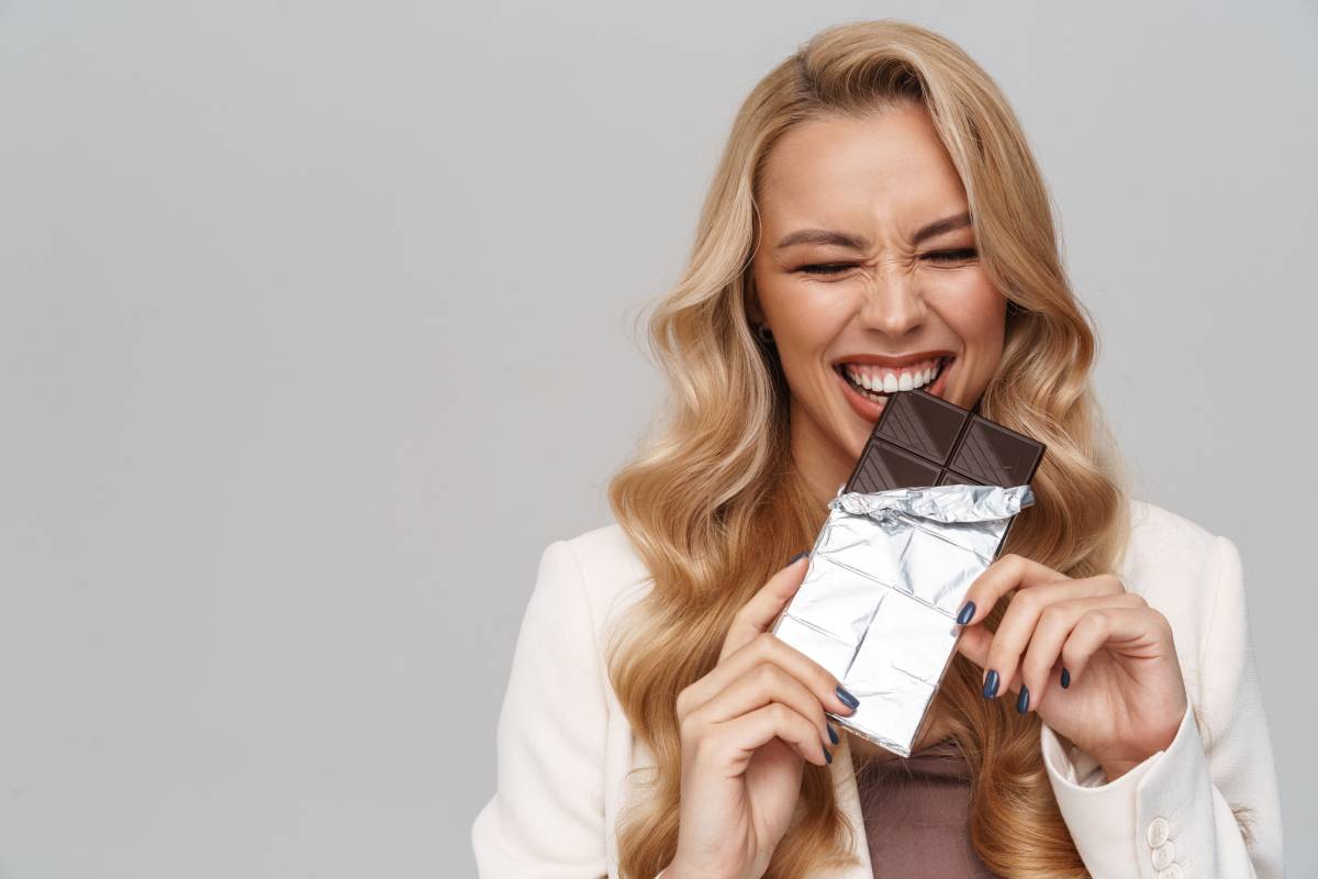 Happy gorgeous woman smiling while eating chocolate