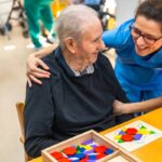 Senior man having fun with nurse playing board skill games