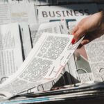 partial view of woman taking daily print newspaper from stand